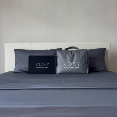 Kosy bedding set with grey bamboo sheets, pillowcases, and packaging displayed neatly on a bed.