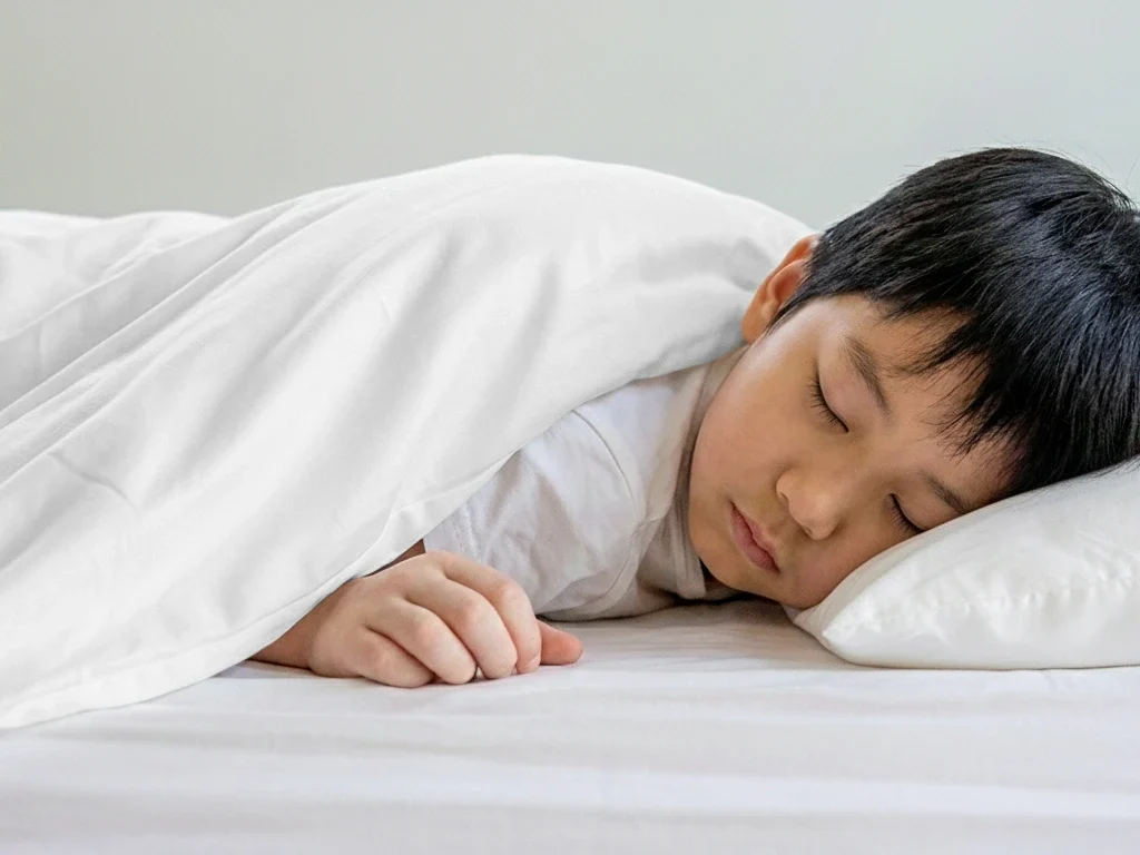 Special needs child sleeping peacefully under a weighted blanket for autism, ADHD, and sensory support